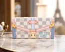 Louis Vuitton Victorine Wallet in Damier Azur canvas with rose ballerine pink trim, gold hardware, and light blue LV monogram, displayed on a marble surface with the Eiffel Tower in the background.