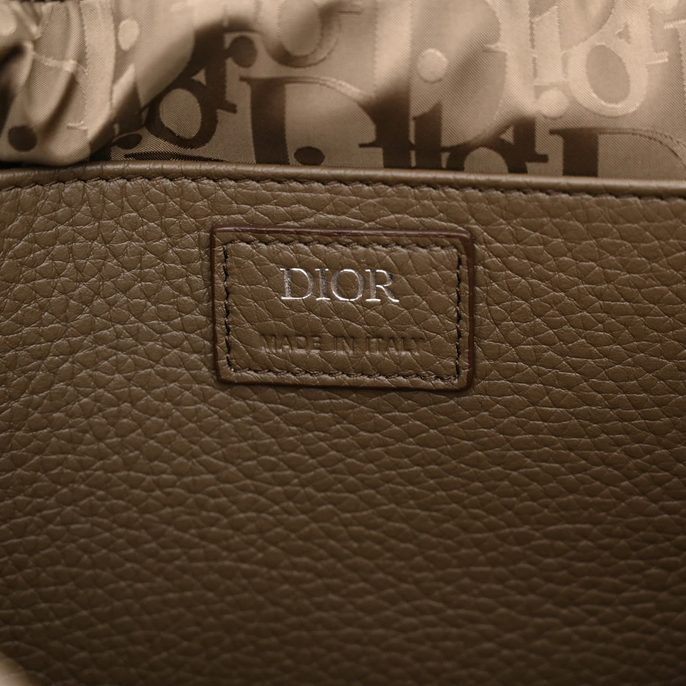 Close-up of the logo detail and silver-tone hardware on the khaki grained calfskin Men's Pillow Bag