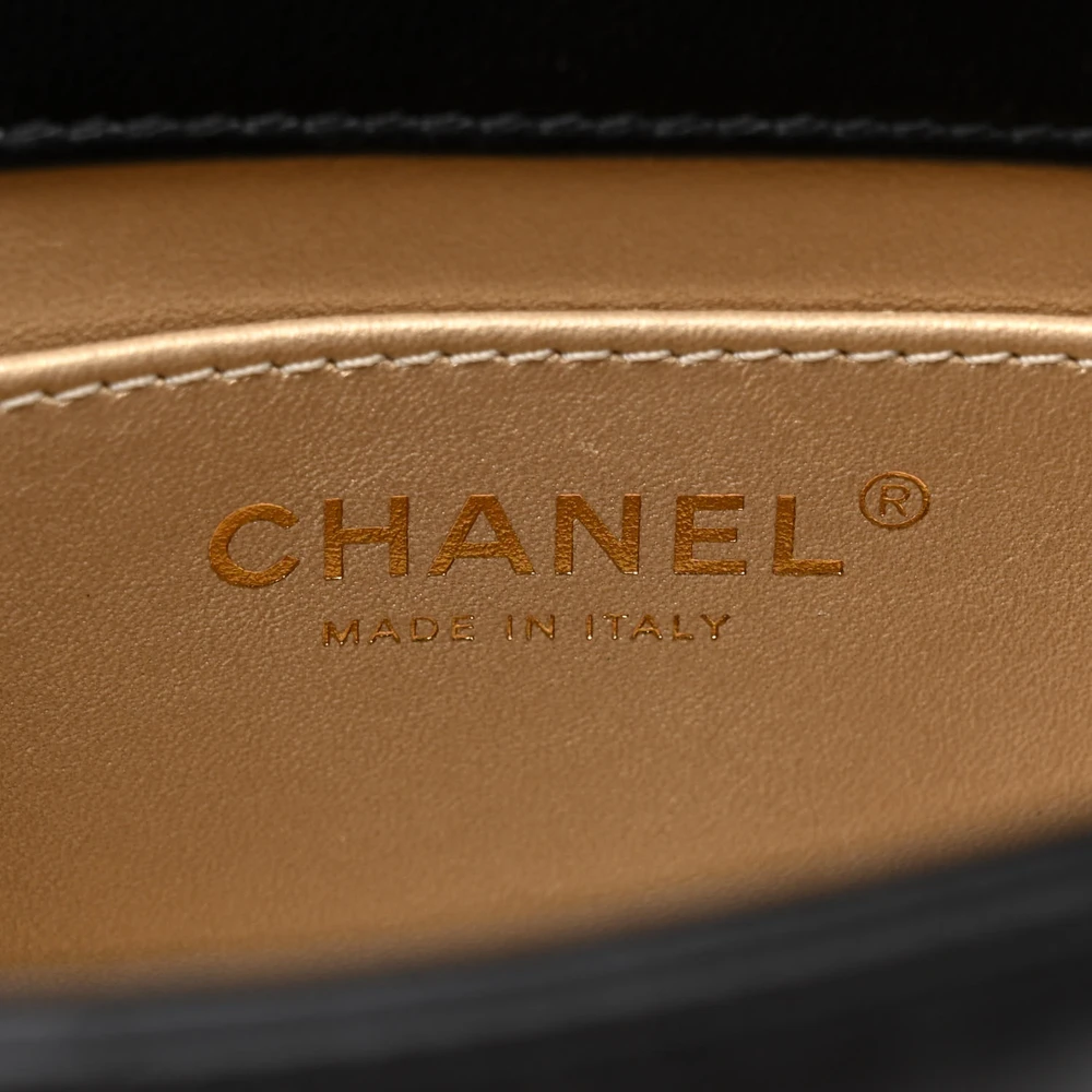 Close-up of the crystal CC logo and aged gold-tone hardware on the black lambskin Chain Flap
