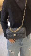 Model carrying the black lambskin Flap Clutch Bag with gold-tone chain strap