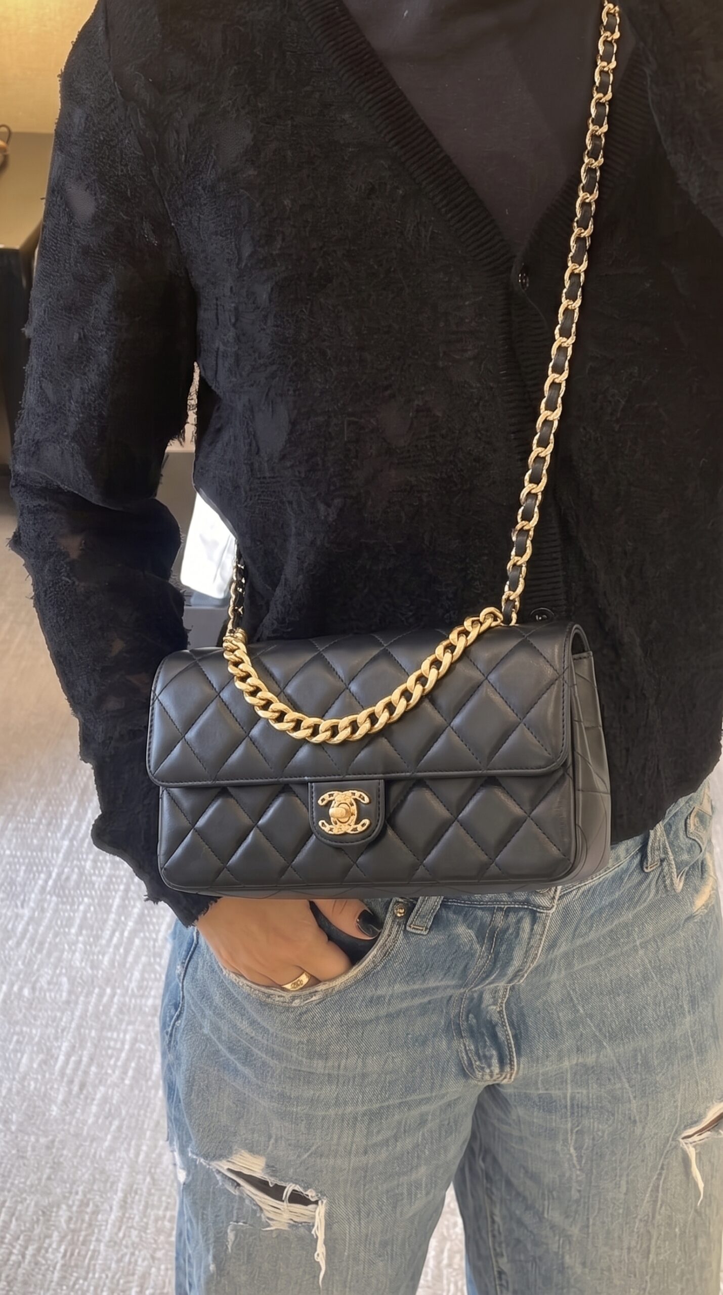 Model carrying the black lambskin Flap Clutch Bag with gold-tone chain strap