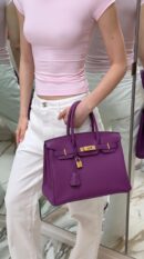 Model carrying the Herme$ Togo Leather Horseshoe Birkin 30 in Anemone and Bleu Electrique Togo leather with gold hardware