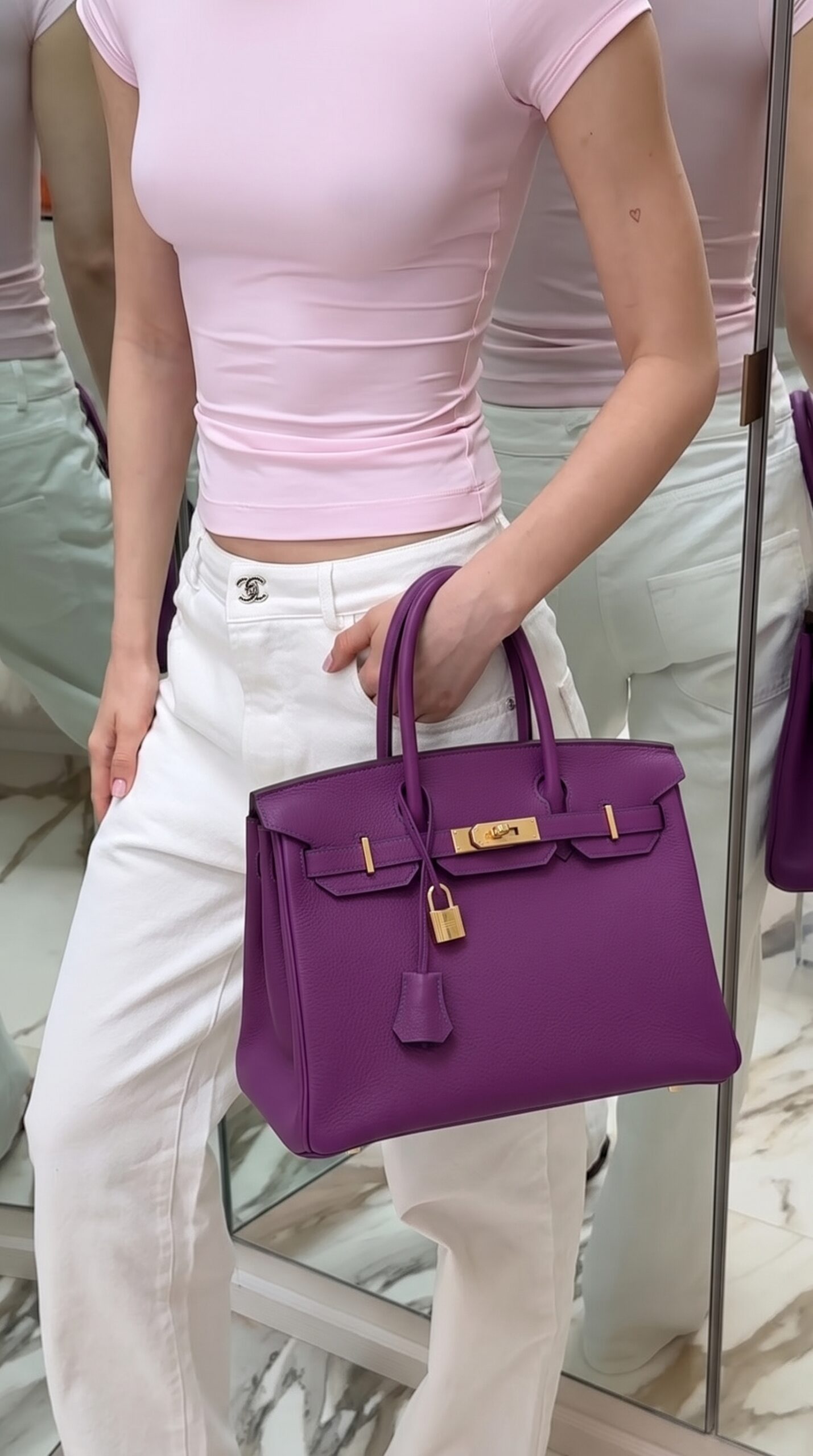 Model carrying the Herme$ Togo Leather Horseshoe Birkin 30 in Anemone and Bleu Electrique Togo leather with gold hardware