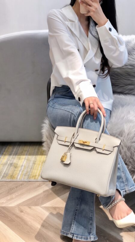 Model carrying the Herme$ Togo Leather Birkin 30 in Beton with gold hardware