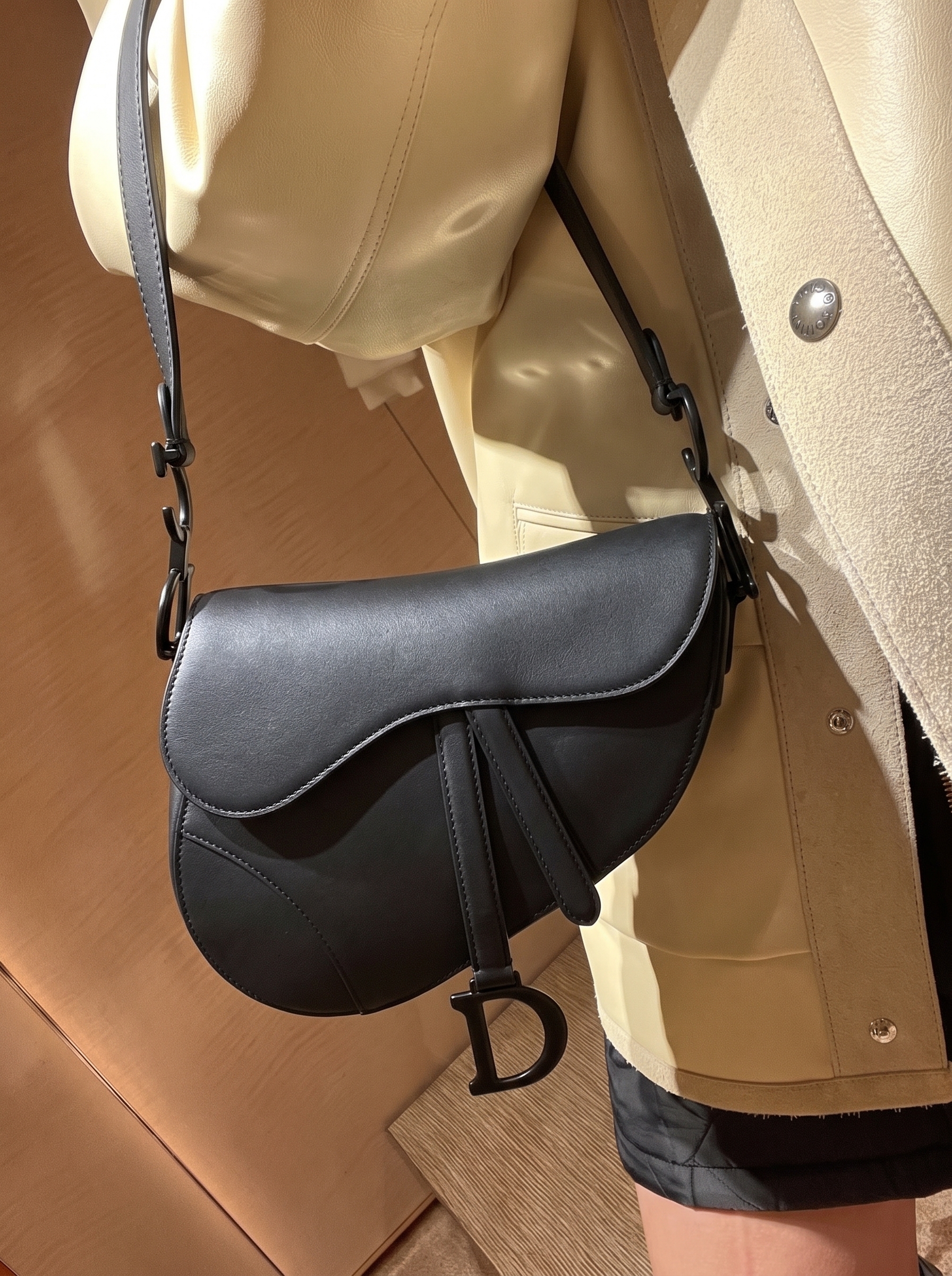 Model holding a black ultra-matte calfskin Saddle Bag over the shoulder