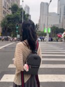 Model wearing a GG Supreme monogram Web Sling Backpack with calfskin leather trim