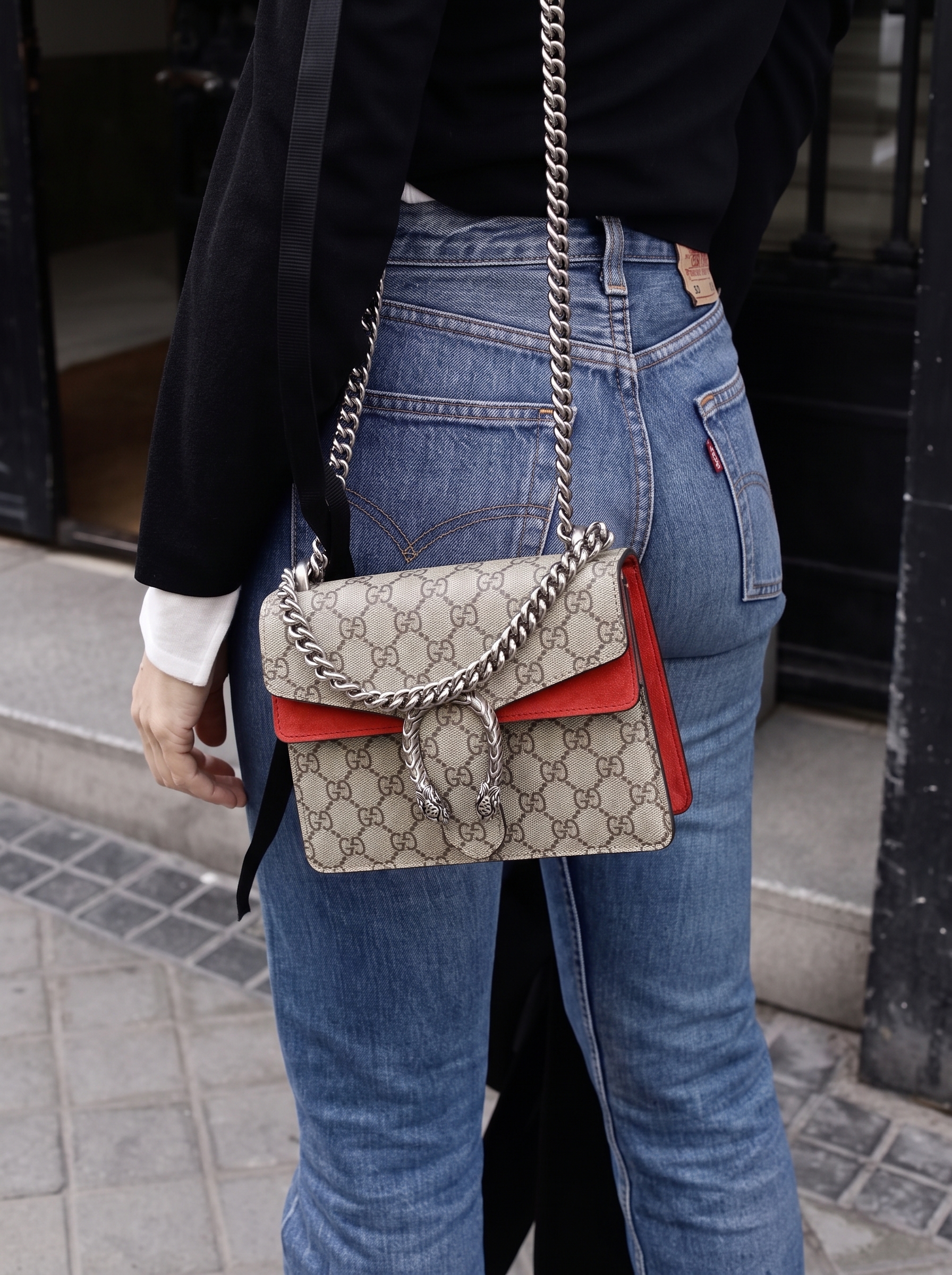 Model carrying a red GG Supreme monogram Small Dionysus shoulder bag with chain shoulder strap