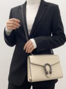 Model carrying a mystic white Dollar calfskin Mini Dionysus chain wallet with chain shoulder strap