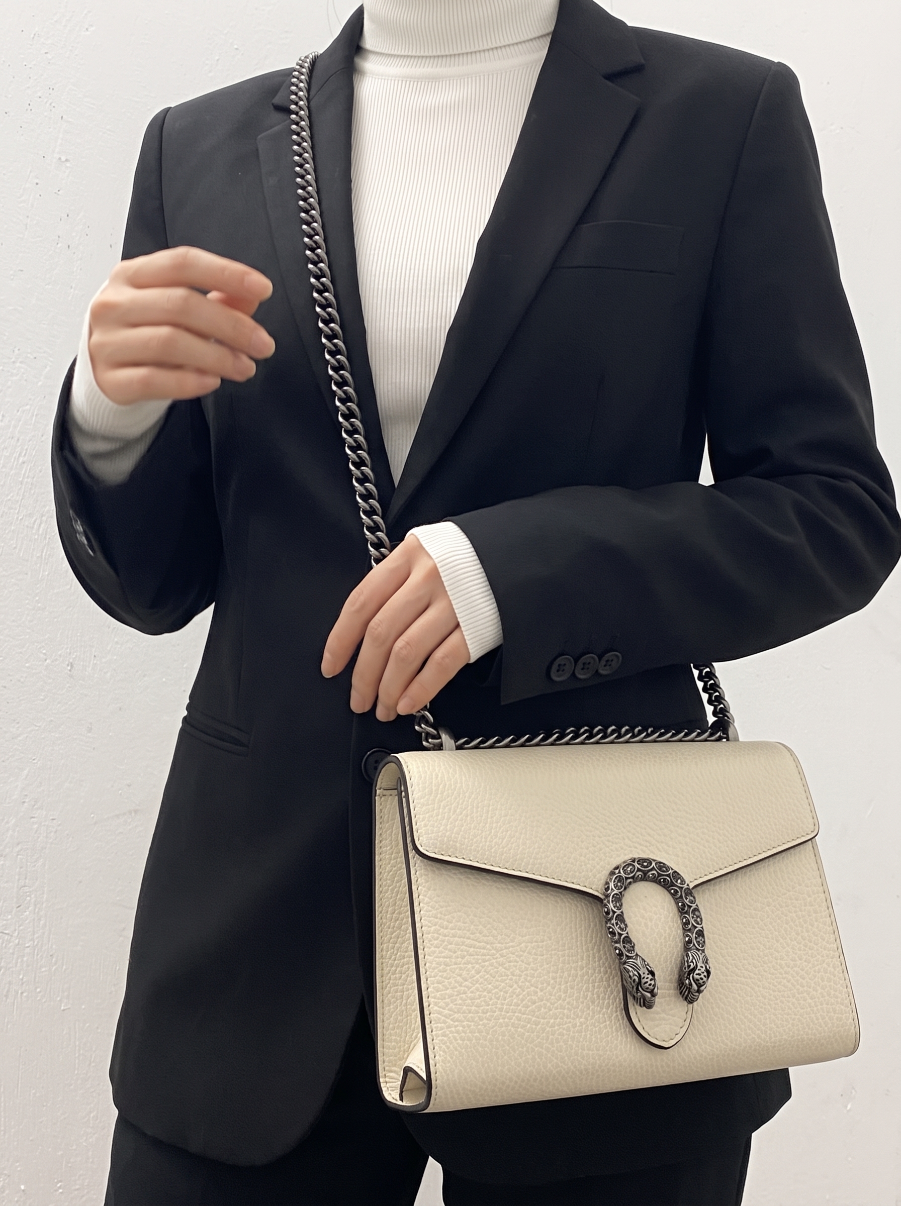Model carrying a mystic white Dollar calfskin Mini Dionysus chain wallet with chain shoulder strap