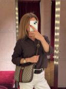 Model carrying a GG Supreme monogram Small OphidiaHalf Moon Hobo with leather shoulder strap