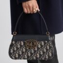 Model carrying a D!0r meduim blue Oblique canvas Medium Key Bag with top handle and shoulder strap