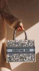 Model carrying D!0r Medium Dioriviera Book Tote Blue Jungle Embroidery