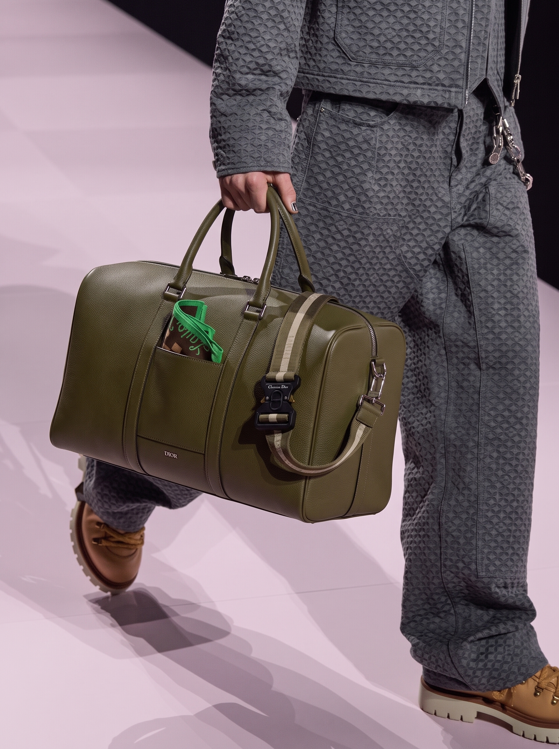 Model carrying an olive green grained calfskin Lingot 50 travel bag with detachable shoulder strap