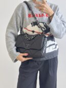 Model carrying the Ch@nel 19 black leather bag with silver hardware and chain shoulder strap