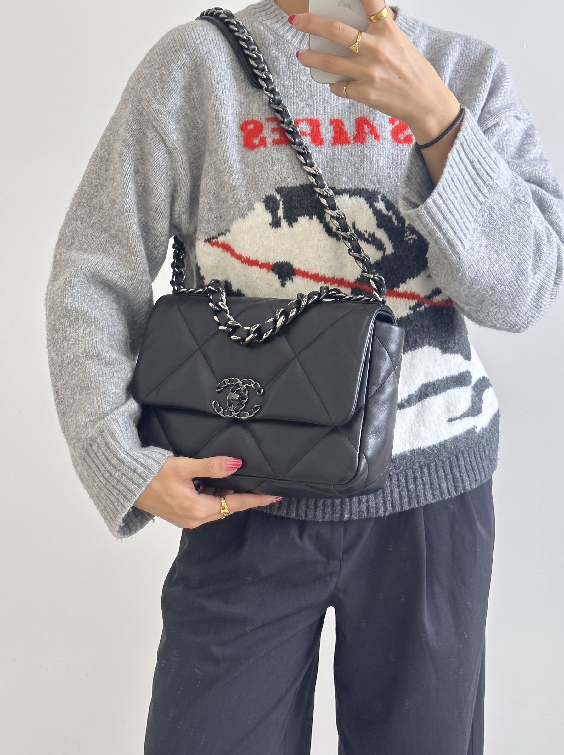 Model carrying the Ch@nel 19 black leather bag with silver hardware and chain shoulder strap