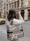 Model carrying the large latte embroidered canvas Book Tote with rolled top handles