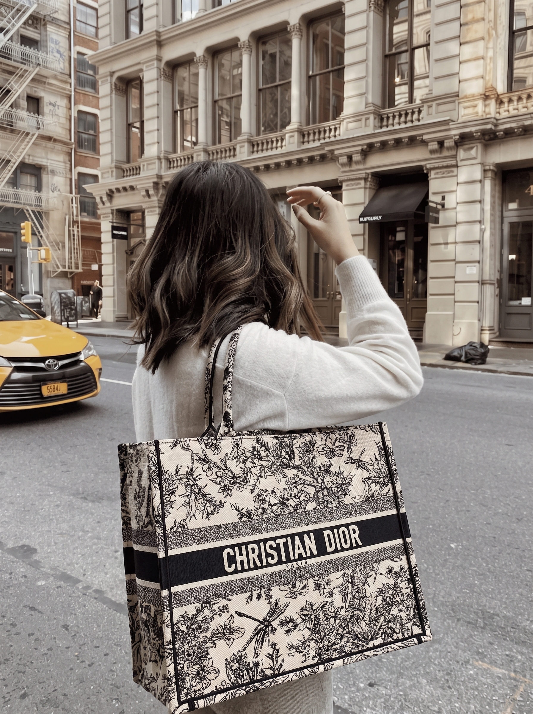 Model carrying the large latte embroidered canvas Book Tote with rolled top handles