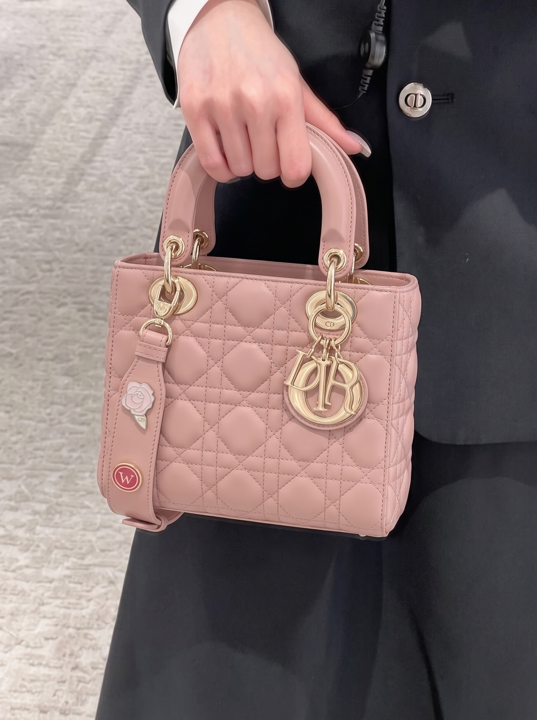 Model carrying the D!0r Light Pink Cannage lambskin small bag with gold-tone hardware and shoulder strap
