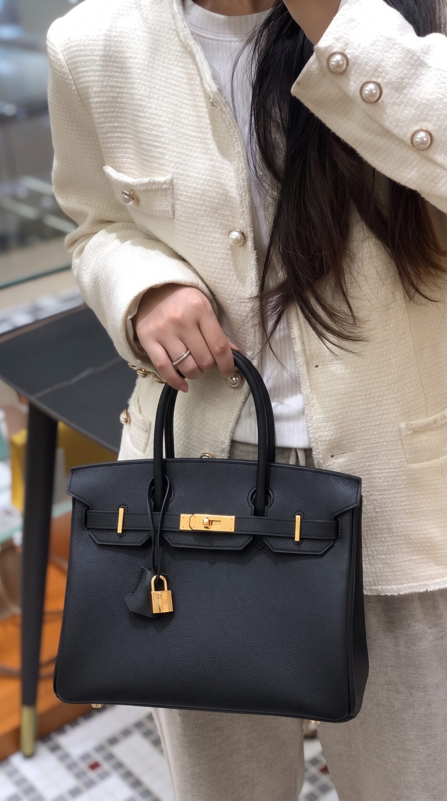 Model carrying the Herme$ Epsom Leather Birkin 30 in Black with gold hardware
