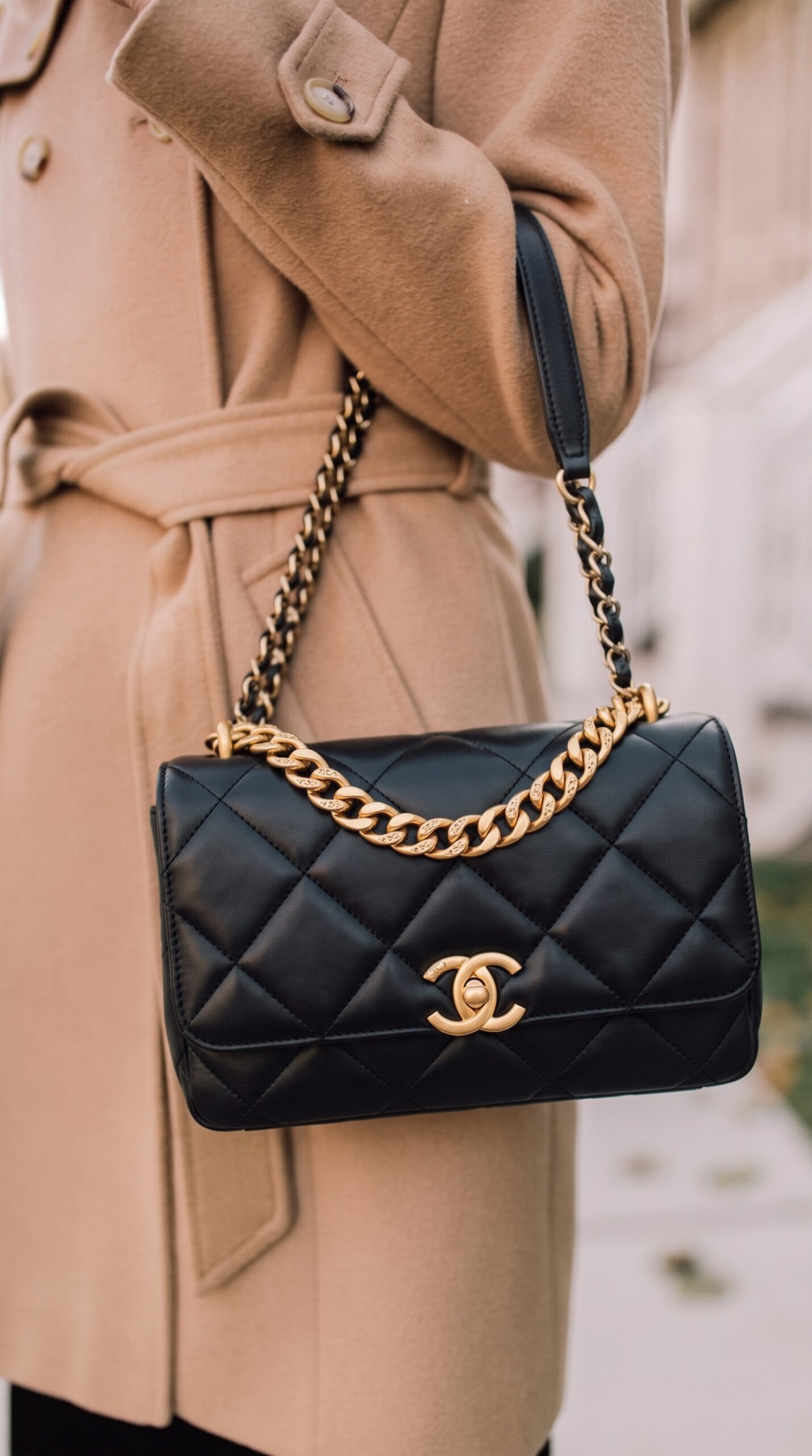 Model carrying the black lambskin Ch@nel CC Crystal Logo Chain Flap with aged gold-tone chain strap